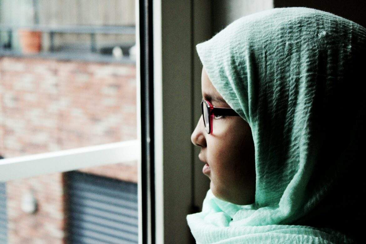 hijabi girl gazes out window