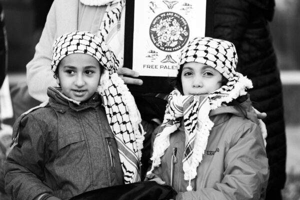 two children wearing keffiyeh at a free palestine rally