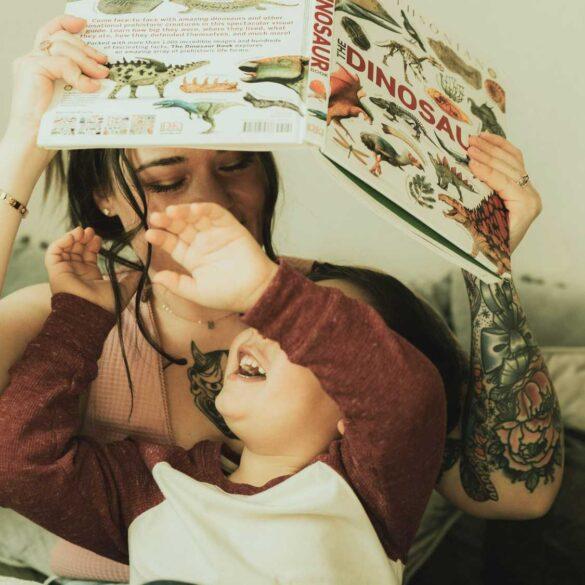 child trying to grab dinosaur book from parent